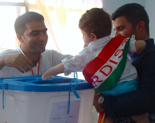 Halabja Voting with child wrapped in flag casting the ballot