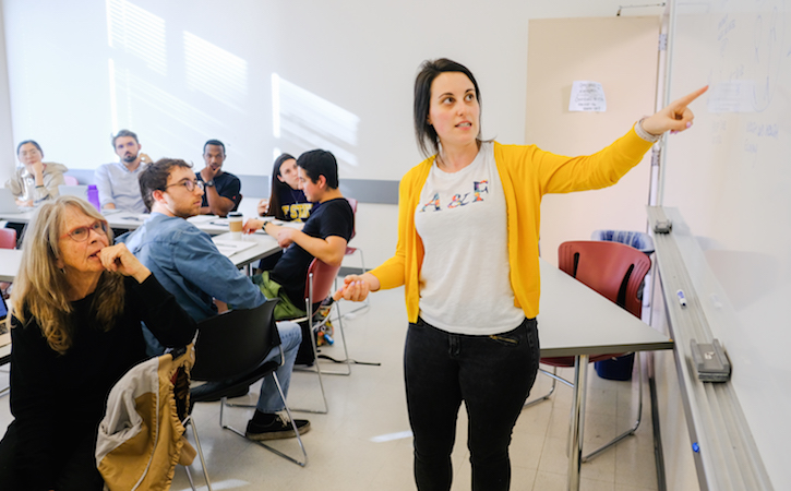 Woman in yellow sweater teaching at front of classroom